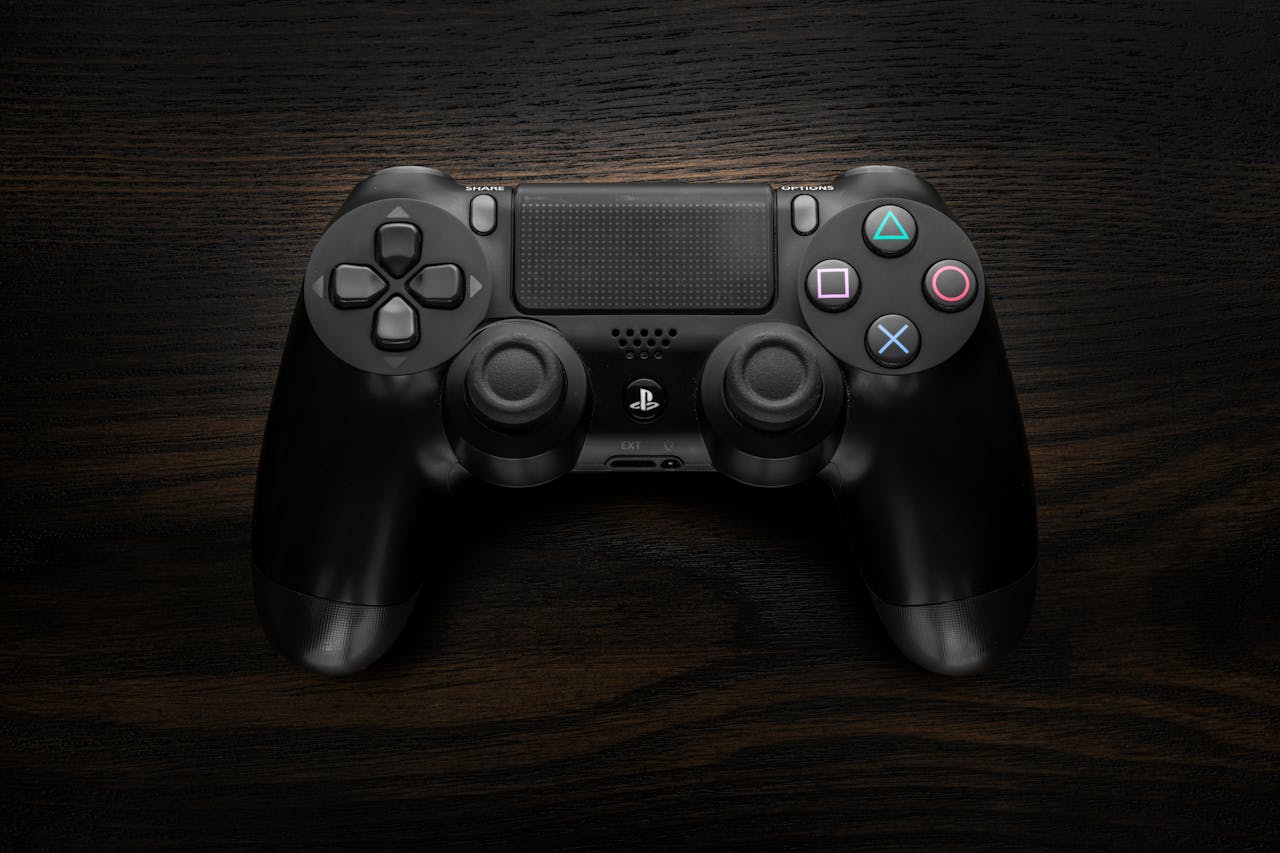 services-05 High-resolution image of a Sony DualShock 4 game controller against a dark wooden background.