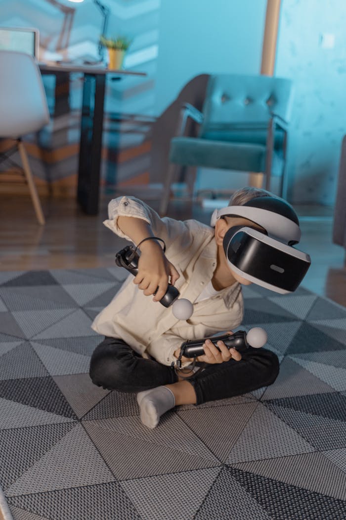 services-06 A young boy sitting on a geometric carpet plays with VR goggles and controllers indoors.
